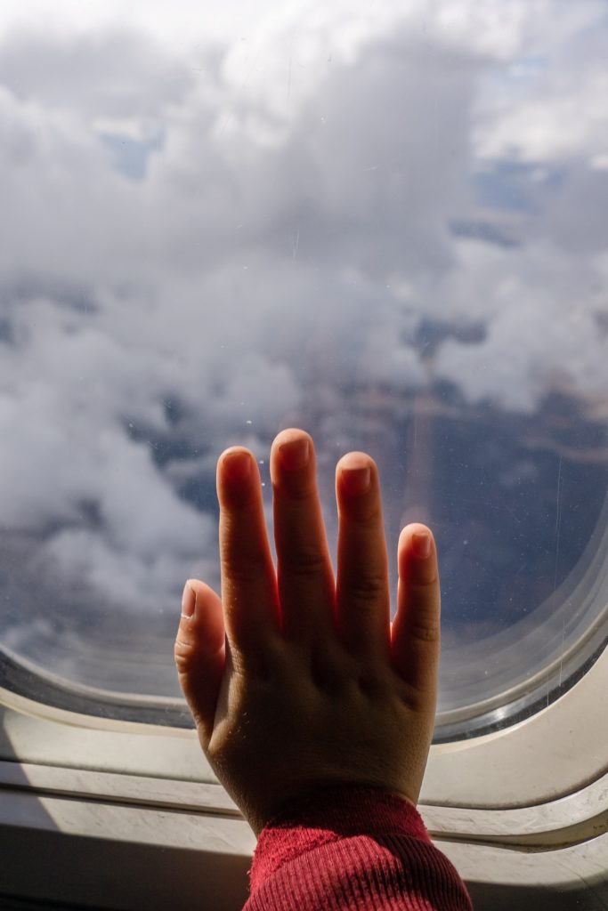A picture of an infant hand in a plane window. Tips for making a long flight smooth with a baby