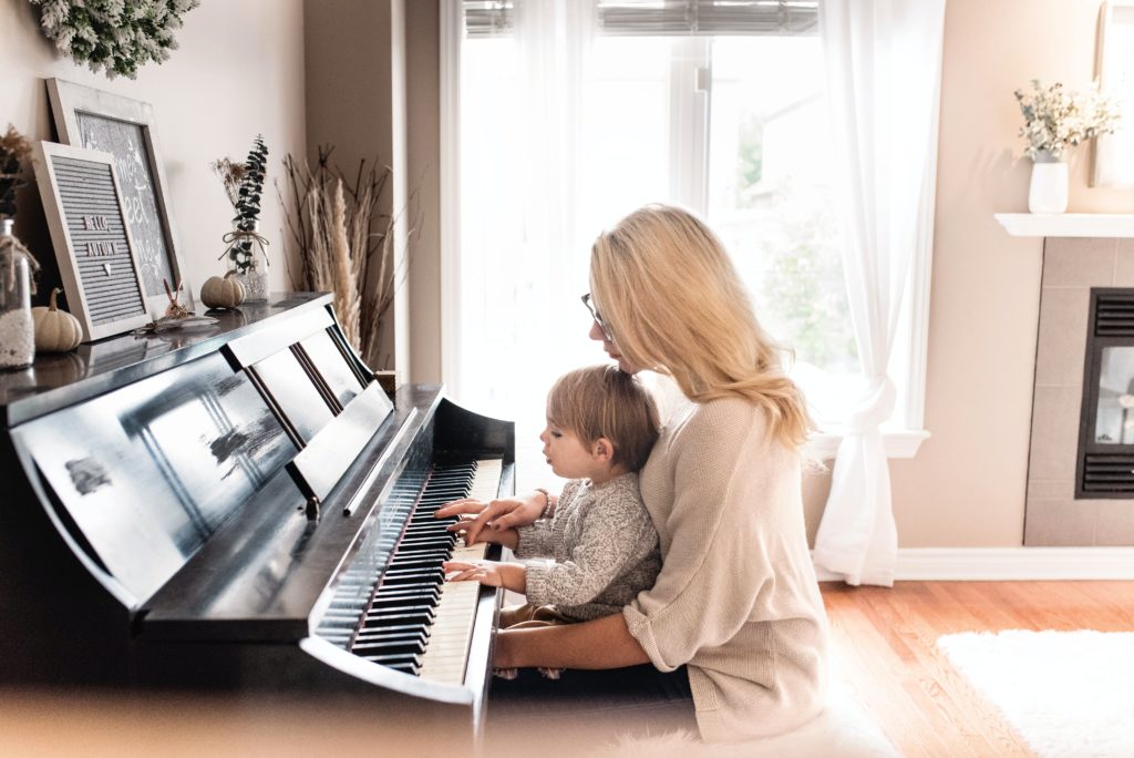 A toddler playing the piano and listening to music for a newborn baby