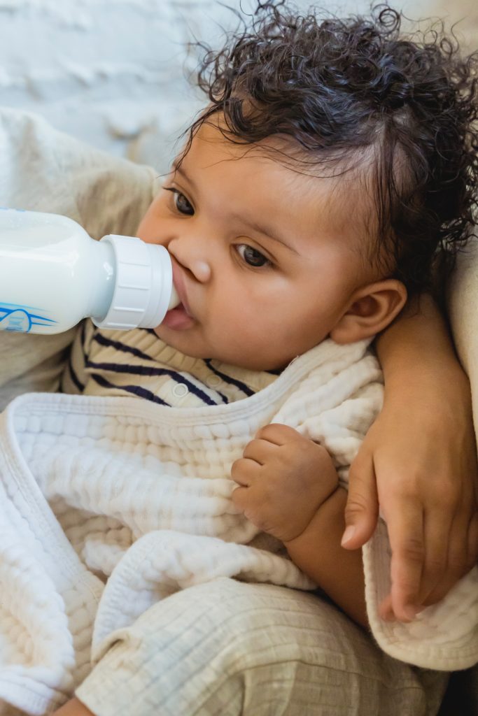 A baby drinking out of a milk bottle what milk baby