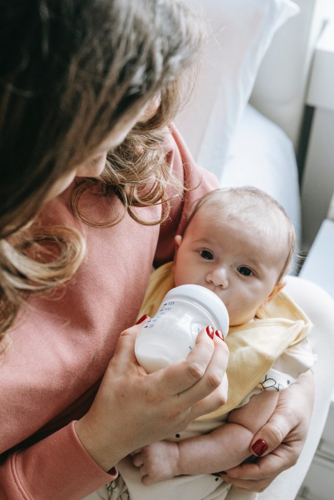 baby drinking a bottle with mom cause baby spit up