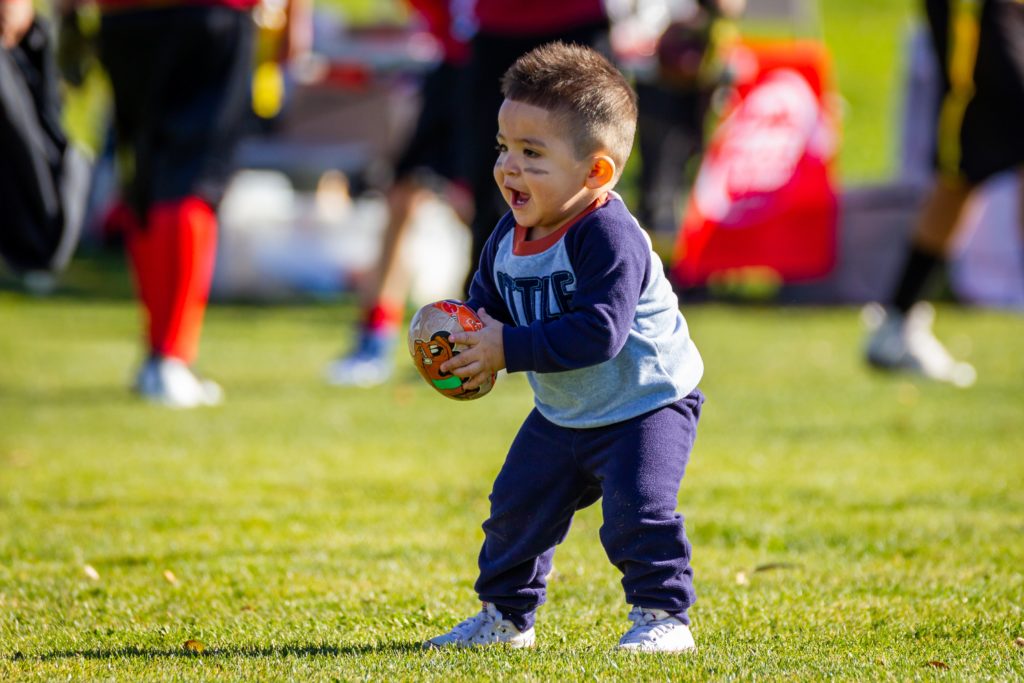 A photo of a toddler with a football bonding baby sport events