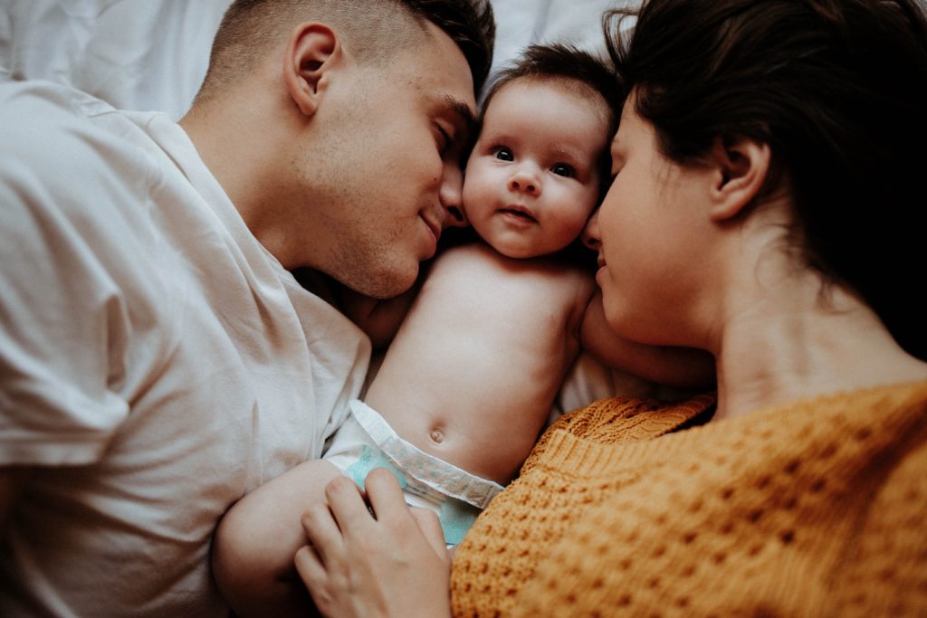 A mom and dad cuddling their baby in an article about the best baby monitors