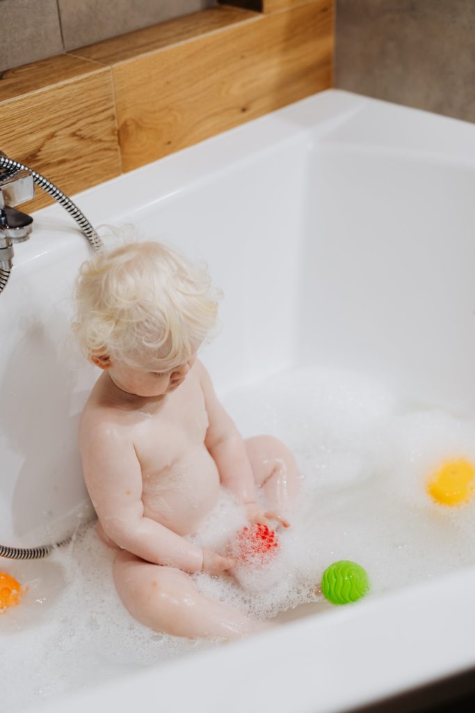 A toddler taking a bath with bath toys