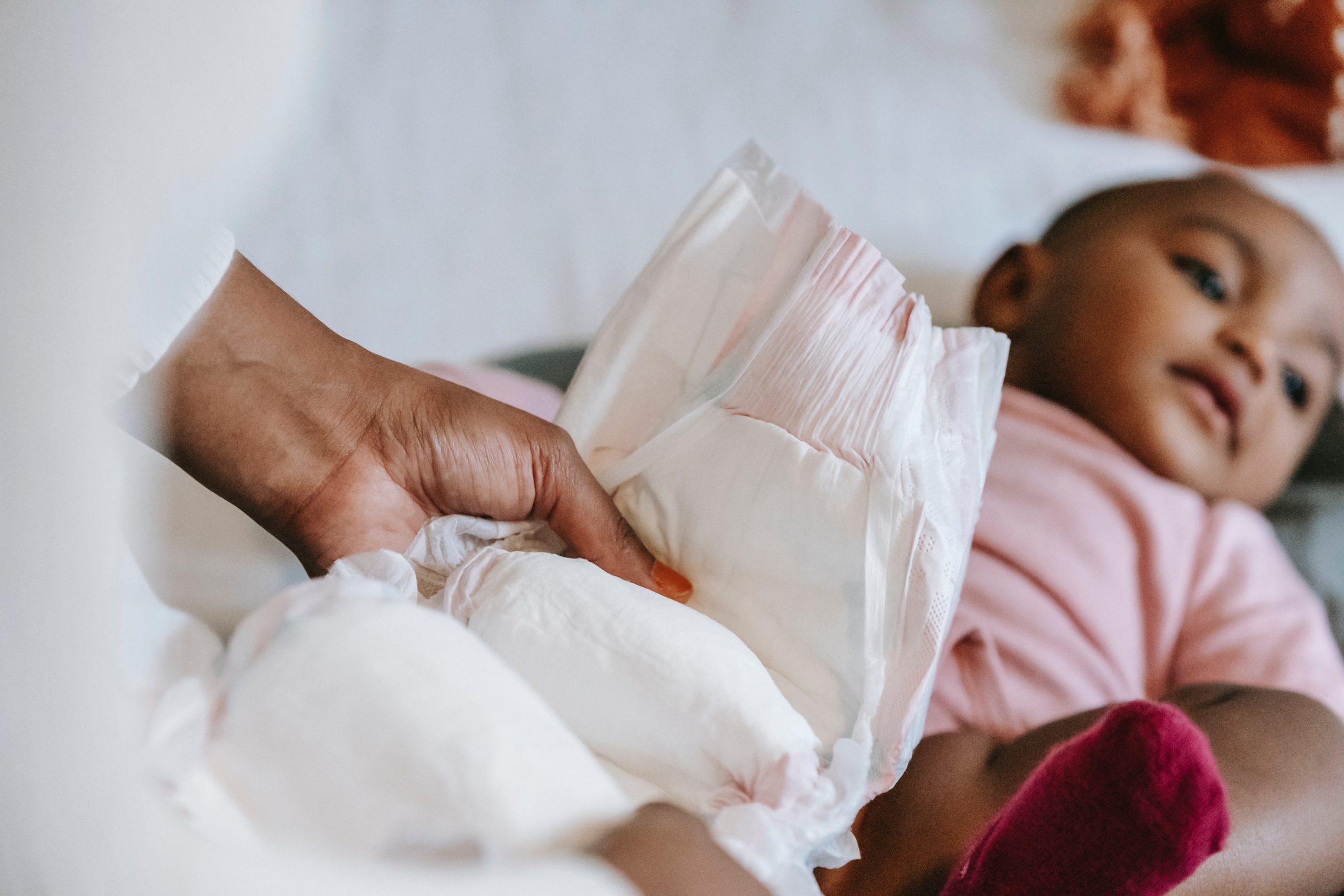 A photo of a parent holding up a diaper in front of baby. Choosing the Best Baby Diapers